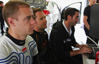 car Jonathon Webb and Michael Patrizi look at the timing screens with engineer